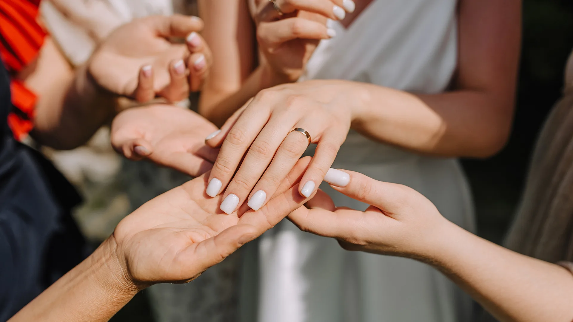 A woman showing off her engagement ring to friends.