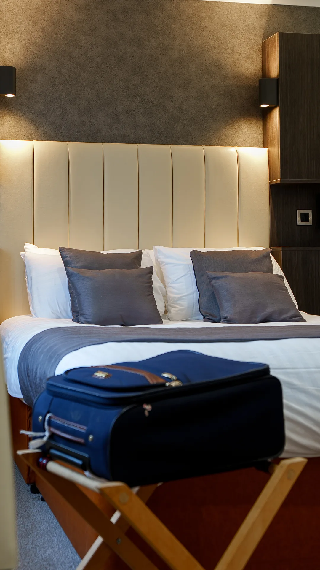 A made bed with a suitcase in front of it. 